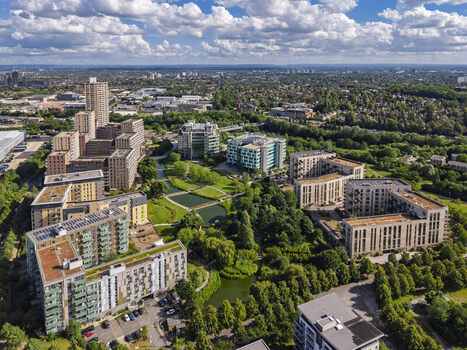 Aerial view of Lakeside Drive featuring modern apartment buildings lush green parkland and a central pond in the urban landscape of London England United Kingdom. Aerial view of Lakeside Drive featuring modern apartment buildings lush green parkland and a central pond in the urban landscape of London England United Kingdom.