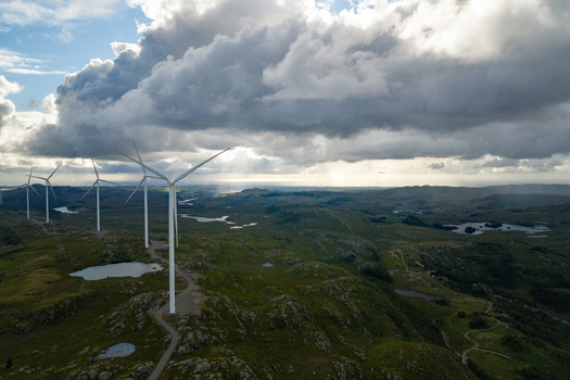 Aerial view of Makaknuten Vindkraftverk wind farm with large turbines set in a rugged rocky landscape with small lakes under dramatic cloudy skies in Bjerkreim Municipality Rogaland Norway. Aerial view of Makaknuten Vindkraftverk wind farm with large turbines set in a rugged rocky landscape with small lakes under dramatic cloudy skies in Bjerkreim Municipality Rogaland Norway.