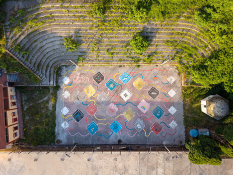 Aerial view of a colorful outdoor court with geometric patterns and an overgrown stone amphitheater surrounded by lush greenery in Kruje Durres County Albania.