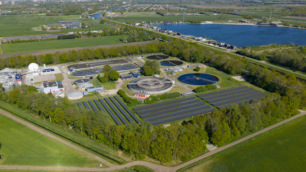 Aerial view of the RWZI Echten wastewater treatment plant featuring circular tanks and solar panels surrounded by green trees and fields in Hoogeveen Drenthe Netherlands. Aerial view of the RWZI Echten wastewater treatment plant featuring circular tanks and solar panels surrounded by green trees and fields in Hoogeveen Drenthe Netherlands.
