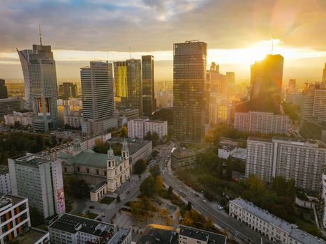 Aerial view of the modern Warsaw city skyline with skyscrapers and a historic church during a golden sunset with autumnal trees Poland. Aerial view of the modern Warsaw city skyline with skyscrapers and a historic church during a golden sunset with autumnal trees Poland.