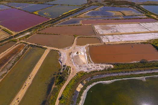 Aerial view of Salinas do Grelha salt pans with vibrant colorful water basins an excavator working on a large pile of salt and dirt paths in Olhao Faro Portugal. Aerial view of Salinas do Grelha salt pans with vibrant colorful water basins an excavator working on a large pile of salt and dirt paths in Olhao Faro Portugal.