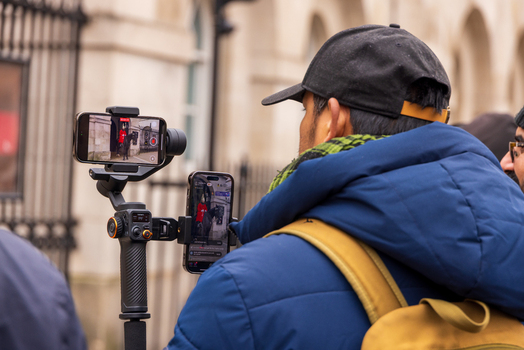 London United Kingdom 12 May 2025 View of a tourist using a gimbal and smartphones to film a King s Guard on horseback at Horse Guards Parade.