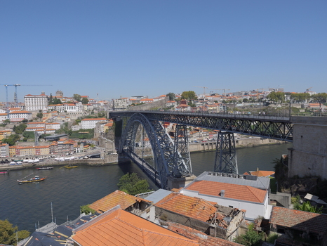 View of the iconic Dom Luis I Bridge spanning the Douro River with historic buildings and terracotta rooftops in the background in Porto Porto District Portugal. View of the iconic Dom Luis I Bridge spanning the Douro River with historic buildings and terracotta rooftops in the background in Porto Porto District Portugal.