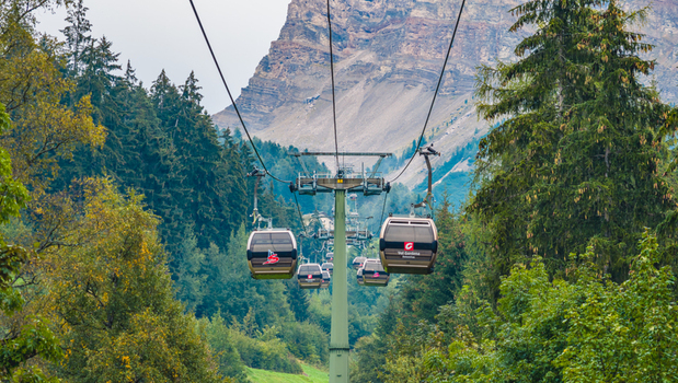 Selva di Val Gardena Italy 18 September 2026 Aerial view of cable car gondolas operating through a forested alpine valley beneath the dramatic mountain slopes of the Dolomites.