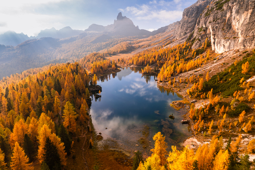 Aerial view of Lago Federa surrounded by golden autumn larch trees with rocky mountain peaks reflected in the calm lake water in Dolomites Cortina d Ampezzo Veneto Italy. Aerial view of Lago Federa surrounded by golden autumn larch trees with rocky mountain peaks reflected in the calm lake water in Dolomites Cortina d Ampezzo Veneto Italy.