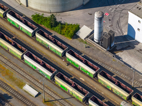 Aerial view of freight train cars parked on parallel tracks in an industrial rail yard with storage silos and concrete structures in Prague Prague Czechia.
