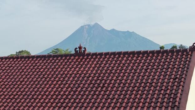 Aerial view of Mount Merapi behind a red tiled roof Indonesia.