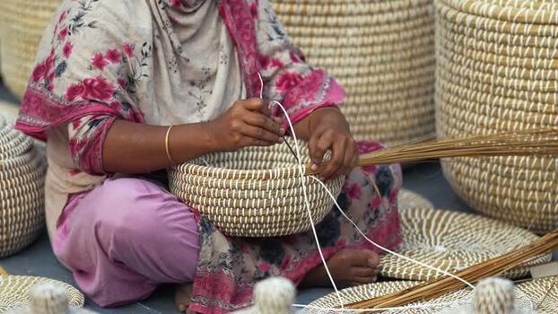 View of a woman weaving traditional baskets in Bogura Bangladesh. View of a woman weaving traditional baskets in Bogura Bangladesh.
