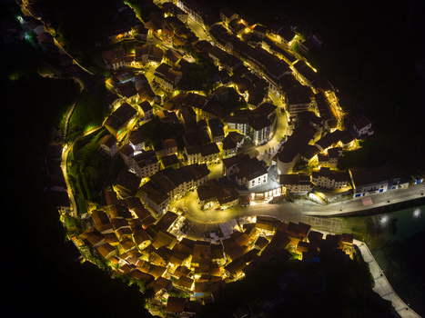 Aerial view of the illuminated coastal town of Cudillero at night with warm streetlights highlighting the traditional houses and central plaza Cudillero Asturias Spain. Aerial view of the illuminated coastal town of Cudillero at night with warm streetlights highlighting the traditional houses and central plaza Cudillero Asturias Spain.