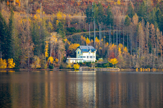 View of a yellow house on the lakefront surrounded by vibrant autumn trees and calm water reflections in Breitnau Baden Wurttemberg Germany. View of a yellow house on the lakefront surrounded by vibrant autumn trees and calm water reflections in Breitnau Baden Wurttemberg Germany.