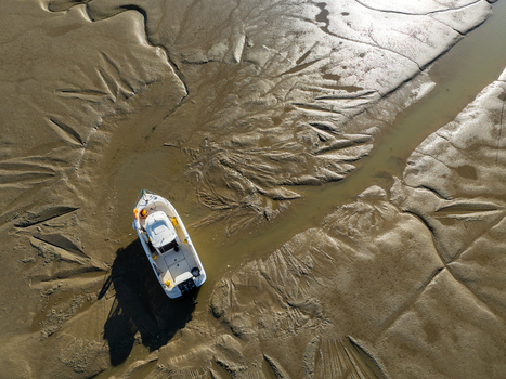 Aerial view of a lone boat stranded in the rippled muddy flats of the Port Ostréicole de Bourcefranc le Chapus Bourcefranc le Chapus France. Aerial view of a lone boat stranded in the rippled muddy flats of the Port Ostréicole de Bourcefranc le Chapus Bourcefranc le Chapus France.