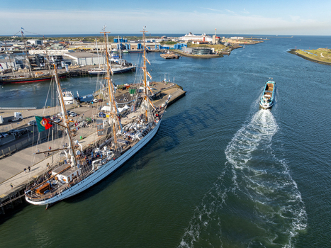 Velsen Netherlands 19 August 2025 Aerial view of a large Portuguese sailing ship NRP Sagres docked at the harbor with industrial buildings and a moving boat in the background. Velsen Netherlands 19 August 2025 Aerial view of a large Portuguese sailing ship NRP Sagres docked at the harbor with industrial buildings and a moving boat in the background.