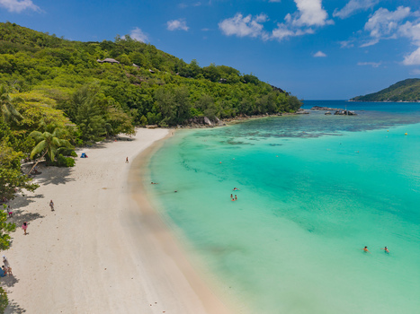 Aerial view of the turquoise waters meet the pristine white sands fringed by lush green hills creating a vibrant coastal paradise Port Launay Mahe Island Seychelles. Aerial view of the turquoise waters meet the pristine white sands fringed by lush green hills creating a vibrant coastal paradise Port Launay Mahe Island Seychelles.