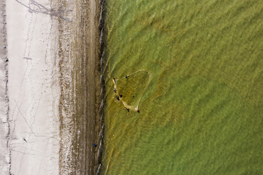 Aerial view of fishermen using a traditional net in the shallow waters along the sandy beach of Kuakata Barisal Division Bangladesh. Aerial view of fishermen using a traditional net in the shallow waters along the sandy beach of Kuakata Barisal Division Bangladesh.