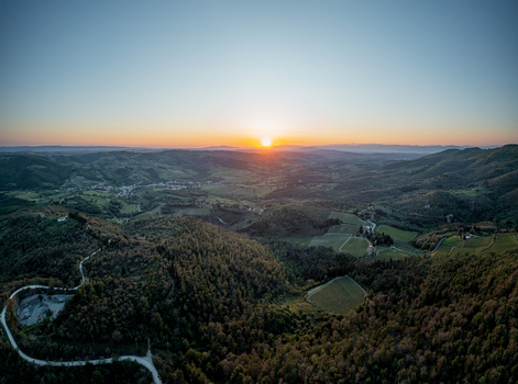 Aerial view of the rolling hills and vineyards of the Chianti region at sunset with lush forests and winding roads in Greve in Chianti Tuscany Italy.
