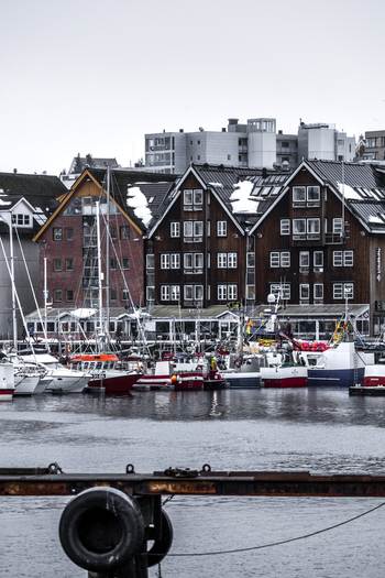 View of traditional wooden buildings and fishing boats moored in the harbour under an overcast winter sky Tromso Troms Norway. View of traditional wooden buildings and fishing boats moored in the harbour under an overcast winter sky Tromso Troms Norway.