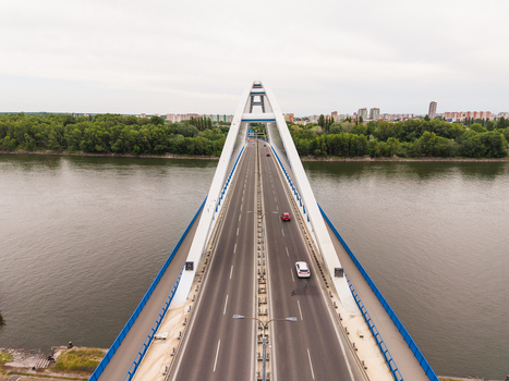 Aerial view of Apollo Bridge spanning the Danube river with cars driving on the asphalt road and green trees on the banks in Bratislava Bratislava Region Slovakia. Aerial view of Apollo Bridge spanning the Danube river with cars driving on the asphalt road and green trees on the banks in Bratislava Bratislava Region Slovakia.
