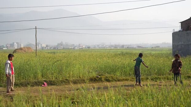 View of children playing in a green field in Surkhet Nepal.