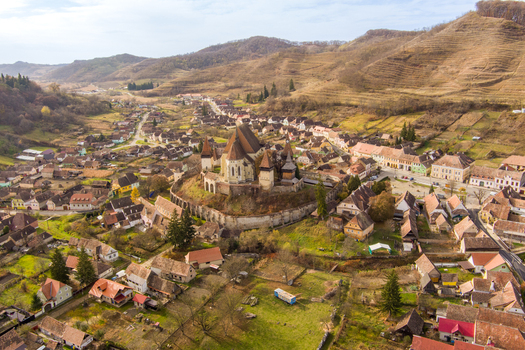 Aerial view of the historic Biertan Fortified Church surrounded by traditional village houses rolling hills and autumn foliage in Biertan Sibiu Romania.