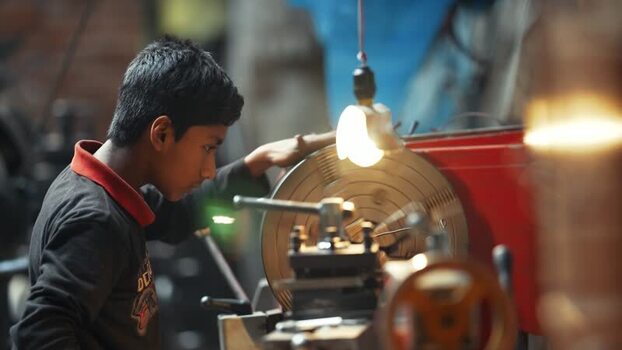 View of a young worker operating a lathe in a workshop Bangladesh.