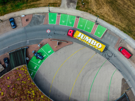 Beilen Netherlands 26 July 2026 Aerial view of a Jumbo truck in a lot with green marked electric vehicle charging stations surrounded by paved surfaces and a green roof.