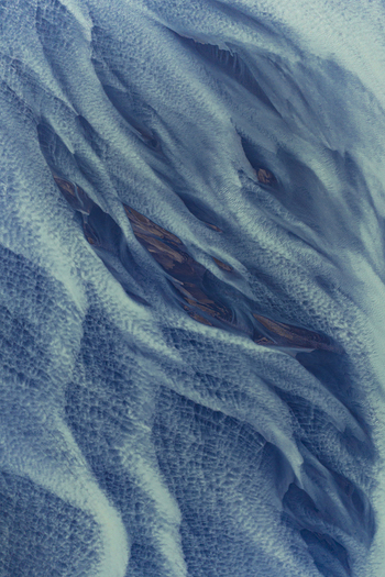 Aerial view of intricate braided glacial river patterns with blue water and dark sediment in Hofn Sveitarfelagid Hornaf Iceland.