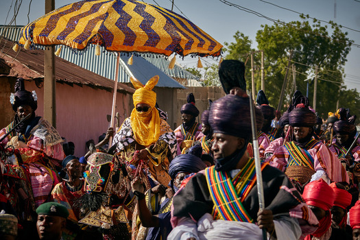 Zaria City Nigerian 21 March 2026 View of a vibrant cultural procession with richly robed figures and a prominent striped umbrella. Zaria City Nigerian 21 March 2026 View of a vibrant cultural procession with richly robed figures and a prominent striped umbrella.