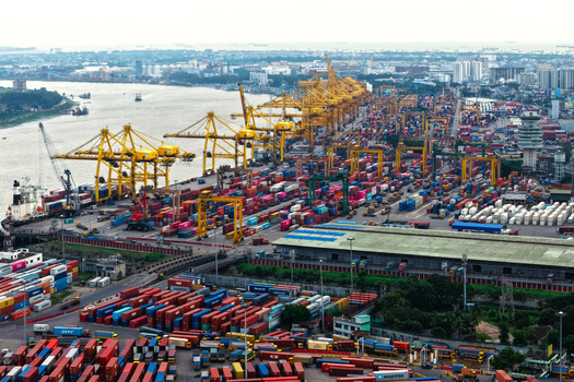 Aerial view of Chattogram Port featuring colorful shipping containers large yellow gantry cranes and industrial infrastructure along the river in Chittagong Chittagong Division Bangladesh.