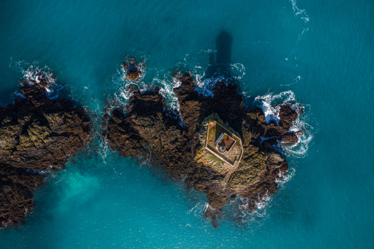 Aerial view of Phare de L Ost Pic lighthouse on a rocky islet with crashing waves and turquoise water in Plouezec France. Aerial view of Phare de L Ost Pic lighthouse on a rocky islet with crashing waves and turquoise water in Plouezec France.