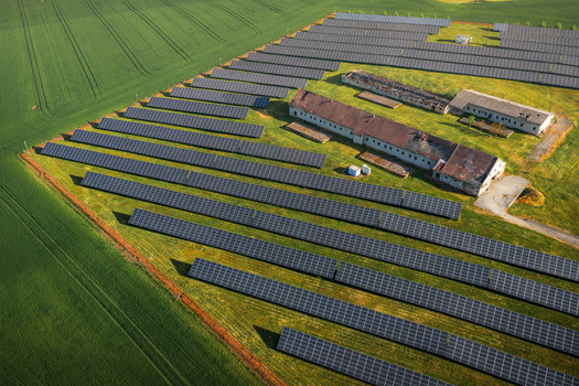 Aerial view of solar panels arranged in rows next to rustic farm buildings and lush green agricultural fields in Chvalkovice Hradec Kralove Region Czechia.