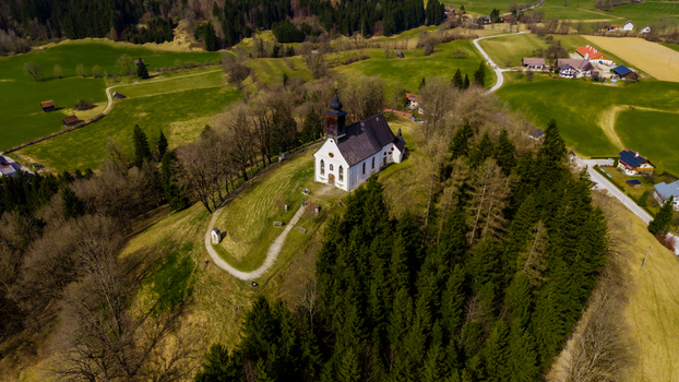 Aerial view of a quaint white church perched atop a hill surrounded by lush green meadows and dense woodlands Windischgarsten Upper Austria Austria. Aerial view of a quaint white church perched atop a hill surrounded by lush green meadows and dense woodlands Windischgarsten Upper Austria Austria.