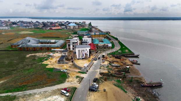 Aerial view of buildings a road and boats moored along the riverbank in the coastal town of Minima Rivers Nigeria.