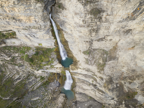 Aerial view of the cascading waterfall in the Pyrenees mountains featuring rugged limestone canyon walls turquoise pools and rocky terrain in Spain. Aerial view of the cascading waterfall in the Pyrenees mountains featuring rugged limestone canyon walls turquoise pools and rocky terrain in Spain.