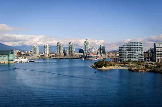 View of the Science World geodesic dome and modern glass skyscrapers along the waterfront of False Creek in Vancouver Canada.