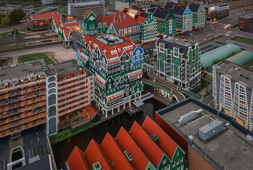 Zaandam Netherlands 26 April 2022 Aerial view of Inntel Hotels Amsterdam Zaandam featuring its iconic stacked green house facade overlooking the canal railway tracks and urban landscape.