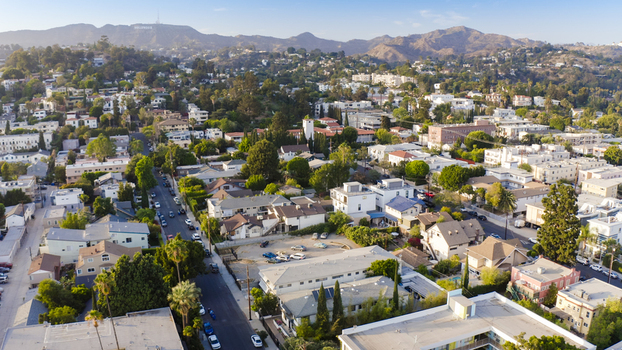 Aerial view of the Hollywood Sign in the distance overlooking the residential neighborhoods and streets of Los Angeles California United States.