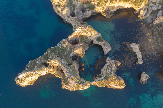 Aerial view of the dramatic rock formations and sea arches of Ponta da Piedade surrounded by turquoise waters in Lagos Faro District Portugal.