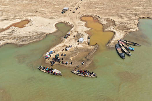 Aerial view of Jadukata River with local people boarding and disembarking from wooden boats along the sandy riverbanks in Sunamganj Sylhet Division Bangladesh. Aerial view of Jadukata River with local people boarding and disembarking from wooden boats along the sandy riverbanks in Sunamganj Sylhet Division Bangladesh.