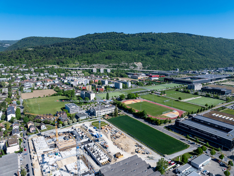 Aerial view of the industrial and residential area of Biel Bienne Bozingenfeld Champ featuring construction sites and sports fields under a clear blue sky in Biel Bienne Canton of Bern Switzerland.