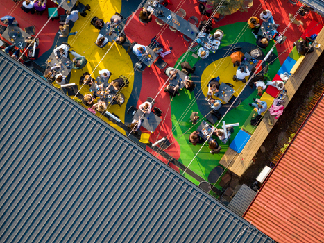 Aerial view of an outdoor restaurant terrace with colorful geometric patterns on the ground featuring people dining at tables under string lights in Belgrade City of Belgrade Serbia. Aerial view of an outdoor restaurant terrace with colorful geometric patterns on the ground featuring people dining at tables under string lights in Belgrade City of Belgrade Serbia.