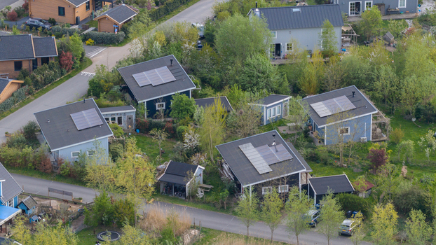 Aerial view of Ecodorp Bolderburen featuring sustainable wooden houses with solar panels on roofs and lush green gardens in Almere Flevoland Netherlands. Aerial view of Ecodorp Bolderburen featuring sustainable wooden houses with solar panels on roofs and lush green gardens in Almere Flevoland Netherlands.