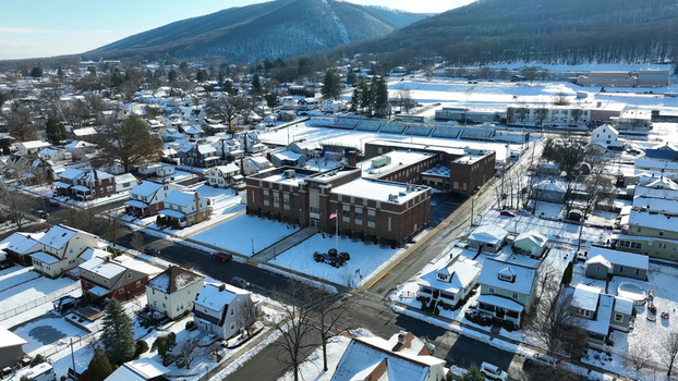Aerial view of a school building surrounded by snow covered residential houses and streets under a clear winter sky in Williamsport Pennsylvania United States.