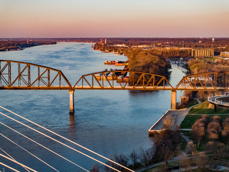 Aerial view of the Big Four Bridge spanning the Ohio River with barges docked along the shore during golden hour Louisville Kentucky United States. Aerial view of the Big Four Bridge spanning the Ohio River with barges docked along the shore during golden hour Louisville Kentucky United States.