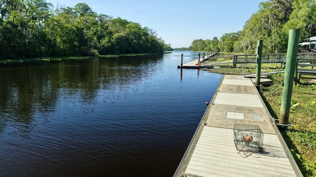 Aerial view of Sixmile Creek with wooden docks lush green trees and a crab trap on the pier in St. Johns County Florida United States.