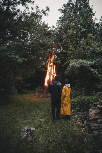 View of a couple standing before a large bonfire in a forest on Vormsi island Laane County Estonia.