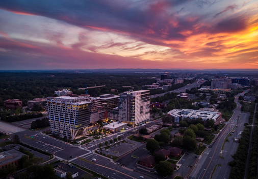 Reston Virginia United States 27 May 2020 Aerial view of modern office buildings and residential complexes surrounded by lush greenery under a vibrant sunset sky. Reston Virginia United States 27 May 2020 Aerial view of modern office buildings and residential complexes surrounded by lush greenery under a vibrant sunset sky.