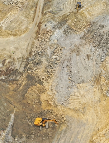 Aerial view of yellow excavators working on a rocky construction site with dirt paths and piles of stones in Avcilar Istanbul Turkey. Aerial view of yellow excavators working on a rocky construction site with dirt paths and piles of stones in Avcilar Istanbul Turkey.