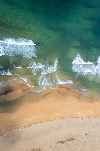 Aerial view of Raudisandur beach with turquoise ocean waves crashing onto the unique red and golden sand in Vesturbyggd Iceland. Aerial view of Raudisandur beach with turquoise ocean waves crashing onto the unique red and golden sand in Vesturbyggd Iceland.