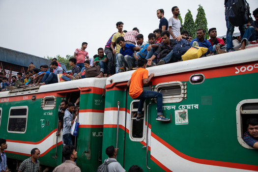 Dhaka Bangladesh 15 June 2018 View of Airport Railway Station with a crowded train where passengers are sitting on the roof and hanging from the doors during the holiday rush. Dhaka Bangladesh 15 June 2018 View of Airport Railway Station with a crowded train where passengers are sitting on the roof and hanging from the doors during the holiday rush.